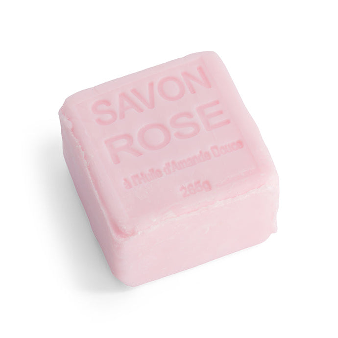 A pink cube soap with the words 'SAVON ROSE' embossed on it, indicating it is a rose-scented soap.