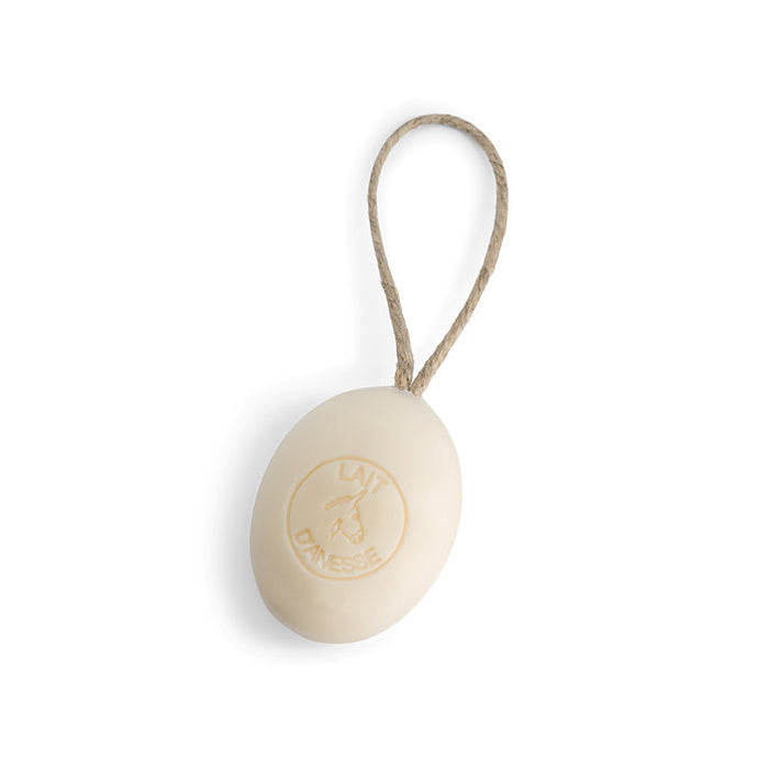 A beige bar of soap with a rope attached, hanging against a white background.