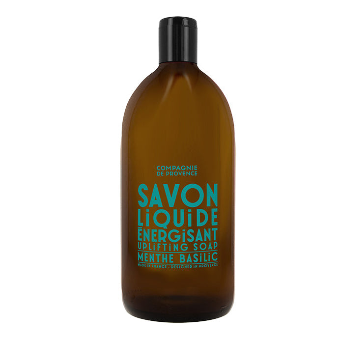 A brown plastic bottle of liquid soap with blue and white label text indicating it is an 'Uplifting Mint Basil' scented product.