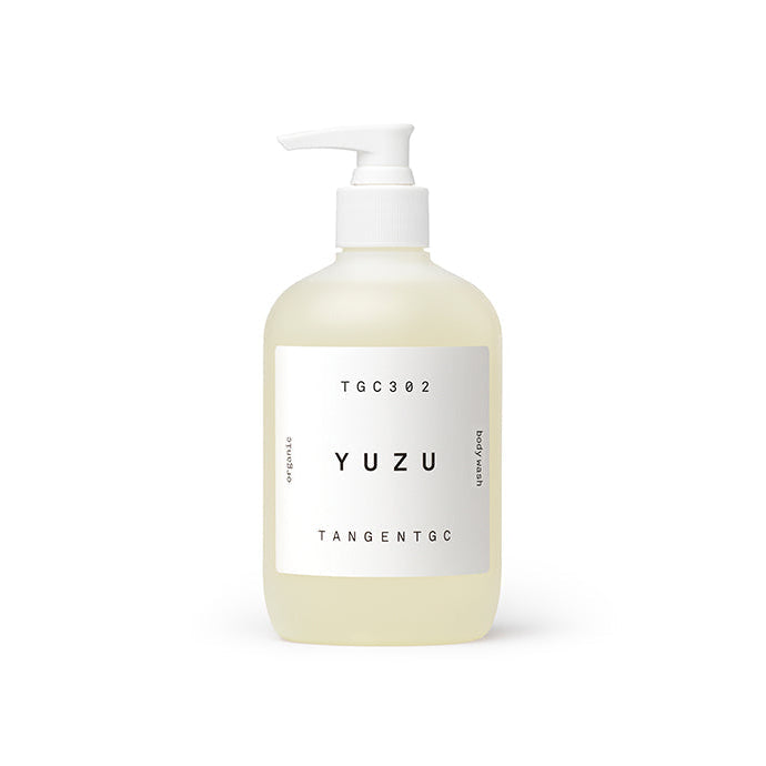 A clear pump bottle with a white label that has 'YUZU' written on it, indicating the scent of the body wash.