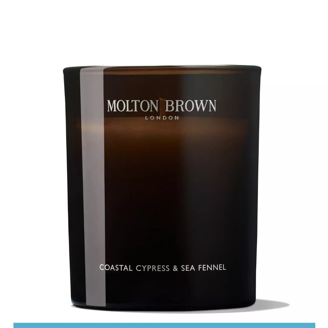 A black candle with a clear label reading 'Molton Brown Coastal Cypress & Sea Fennel'.